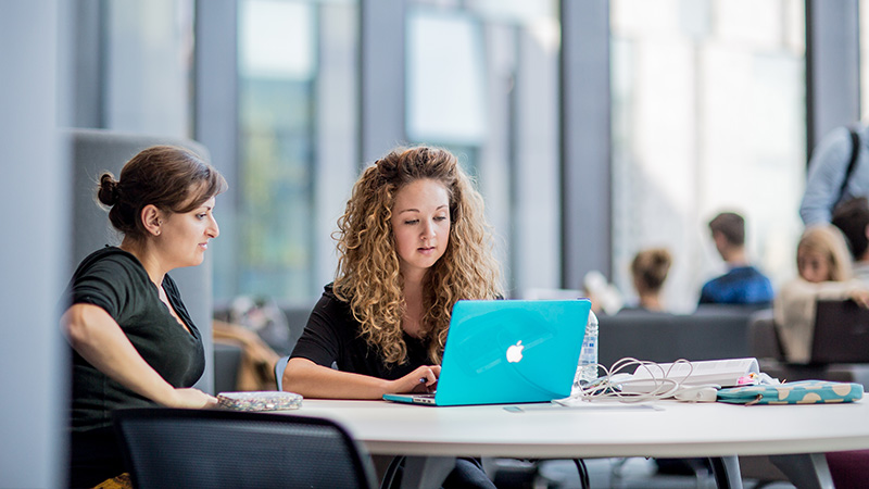Two students looking at a laptop Two students looking at a laptop