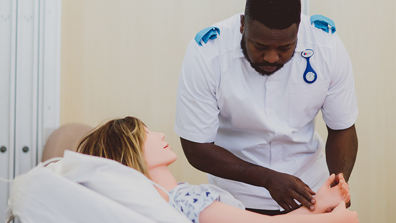 Male nurse finding a pulse on a medical dummy