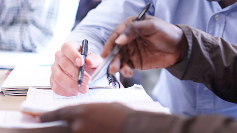 two hands holding pens