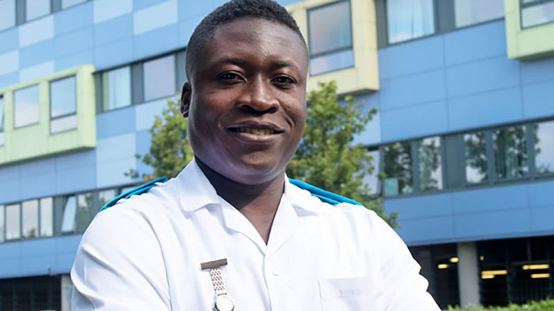 Male nurse stood in front of a hospital