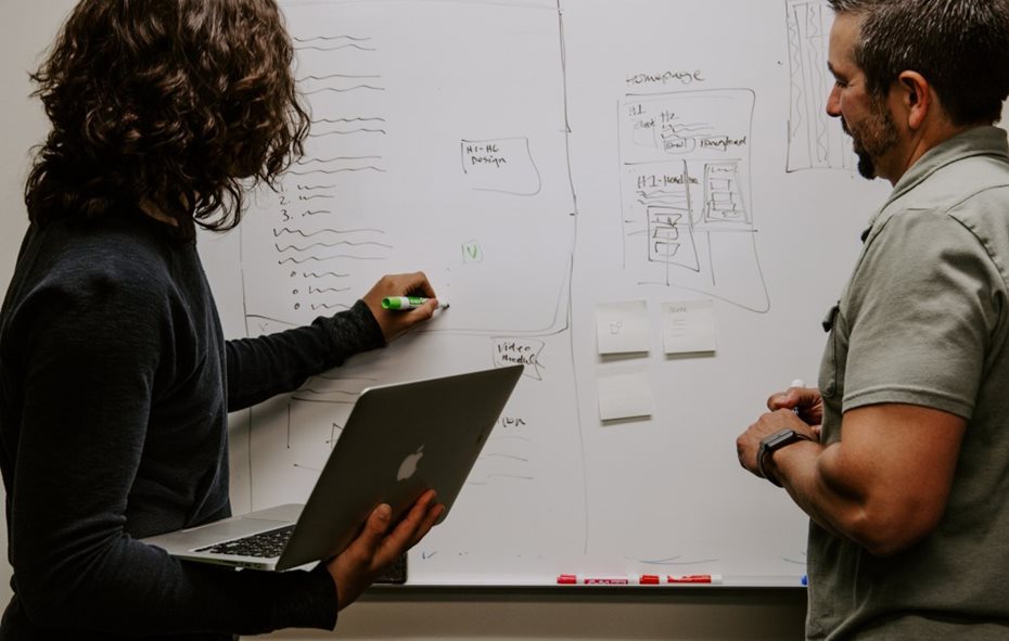 two people planning in front of a whiteboard