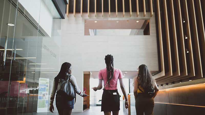Three girls walking through campus