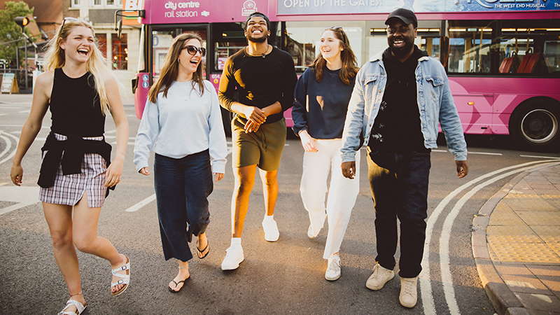 Group of students walking down street laughing 