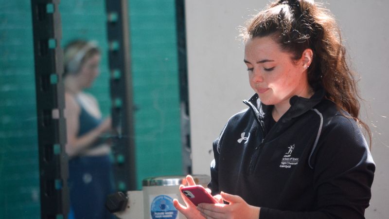 Anna checking fitness on her smartphone in gym