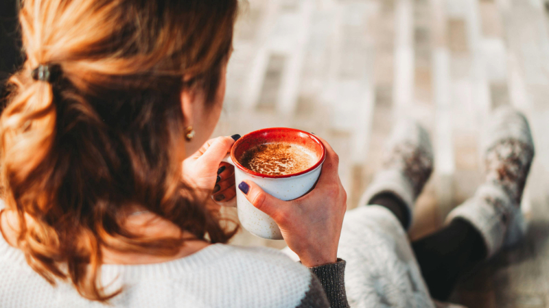 A woman enjoys a warm, non-alcoholic beverage