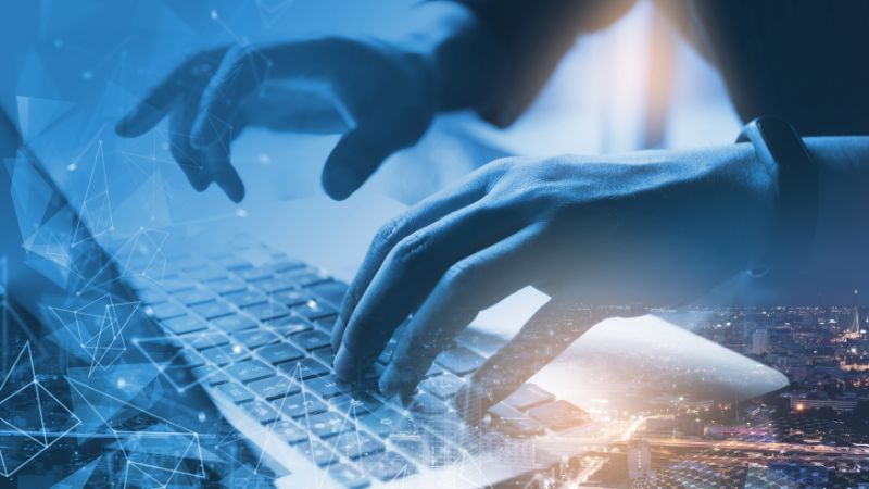 hands typing on a laptop with abstract shapes around it