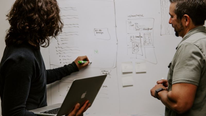 two people in front of a whiteboard writing down ideas