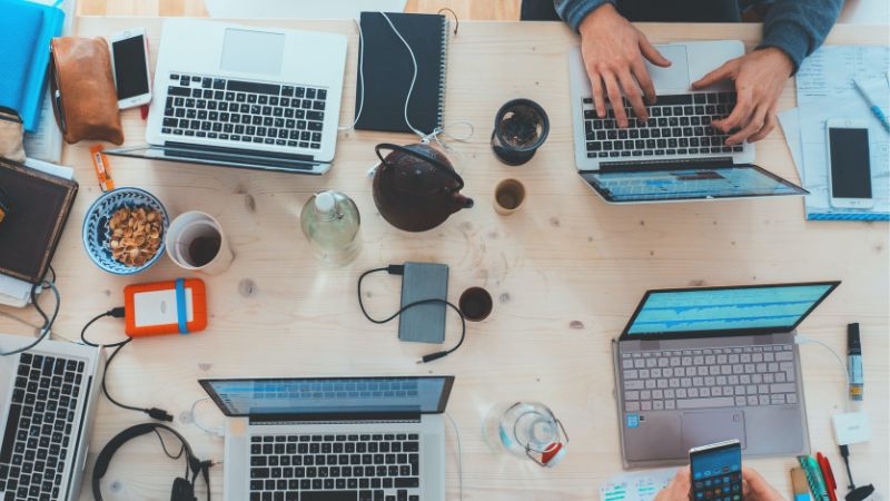 people working on computers on a busy desktop