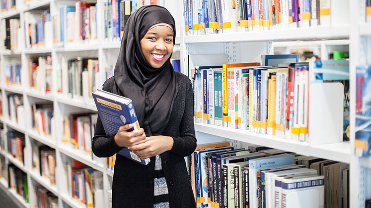 student with a book in the library