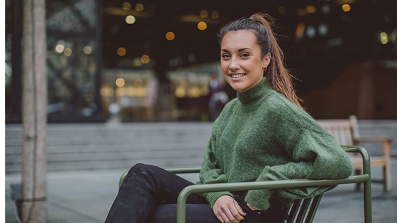 Student smiling sat on a desk